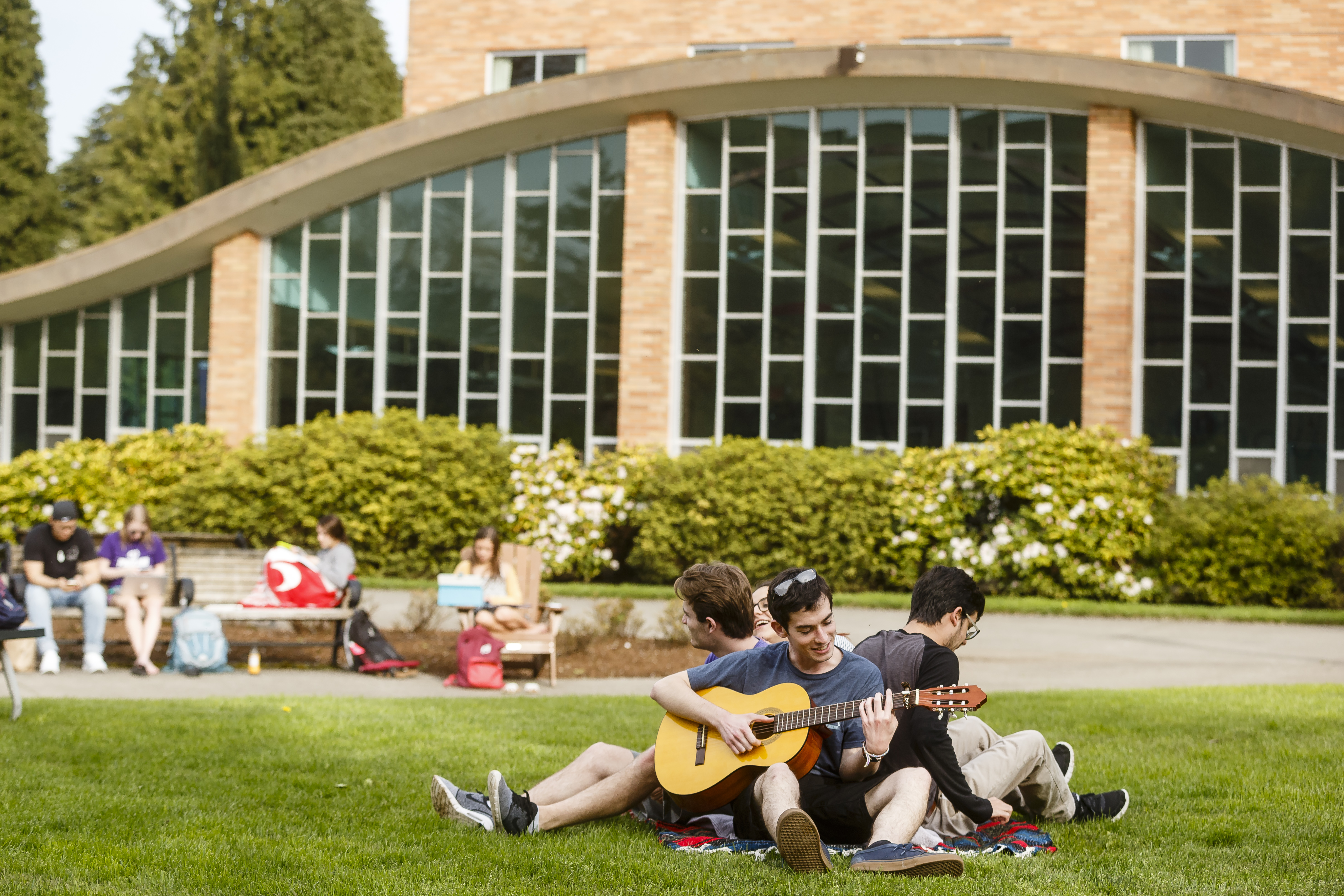 students sitting outside of a residence hall enjoying outdoor activities