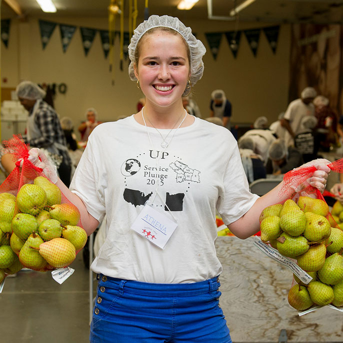 female student in hair net holding two bags of fruit