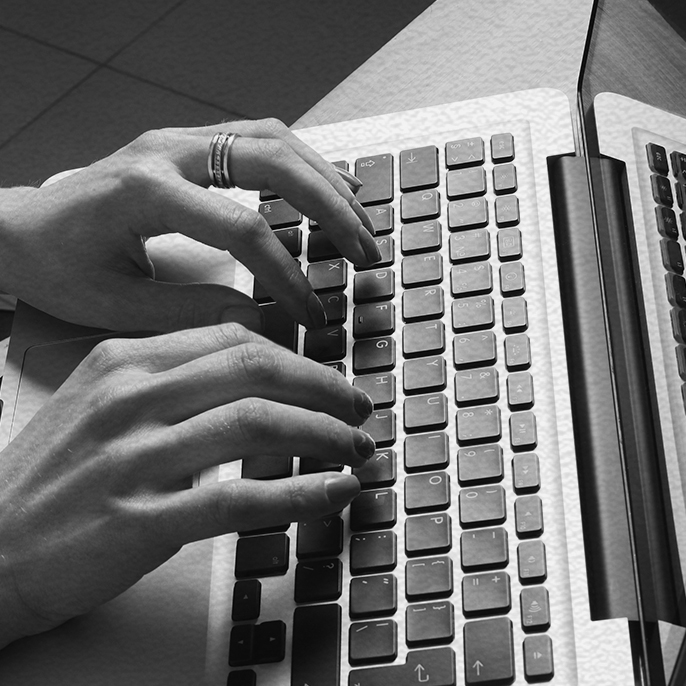 close-up of hands typing on a laptop keyboard.