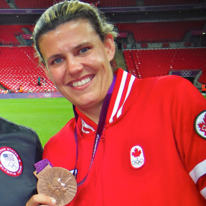 Photo of Christine Sinclair '06 holding up her Olympic bronze medal.