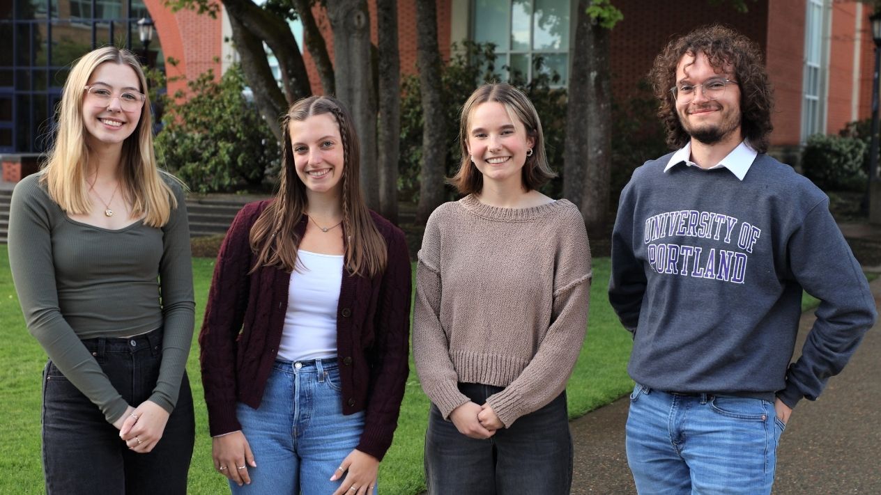 Student scholarship recipients pose in front of a campus building