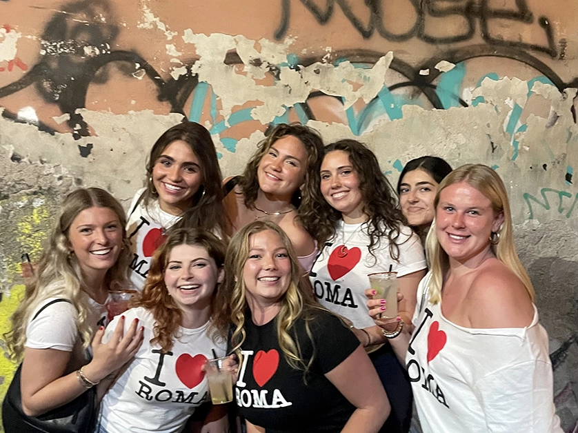 Students in matching shirts pose in a Roman alley