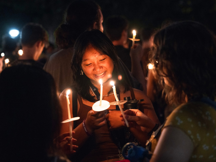 A student lights a candle at the bell tower ceremony