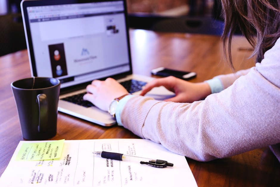 Woman working on a computer with a pen and planner on desk