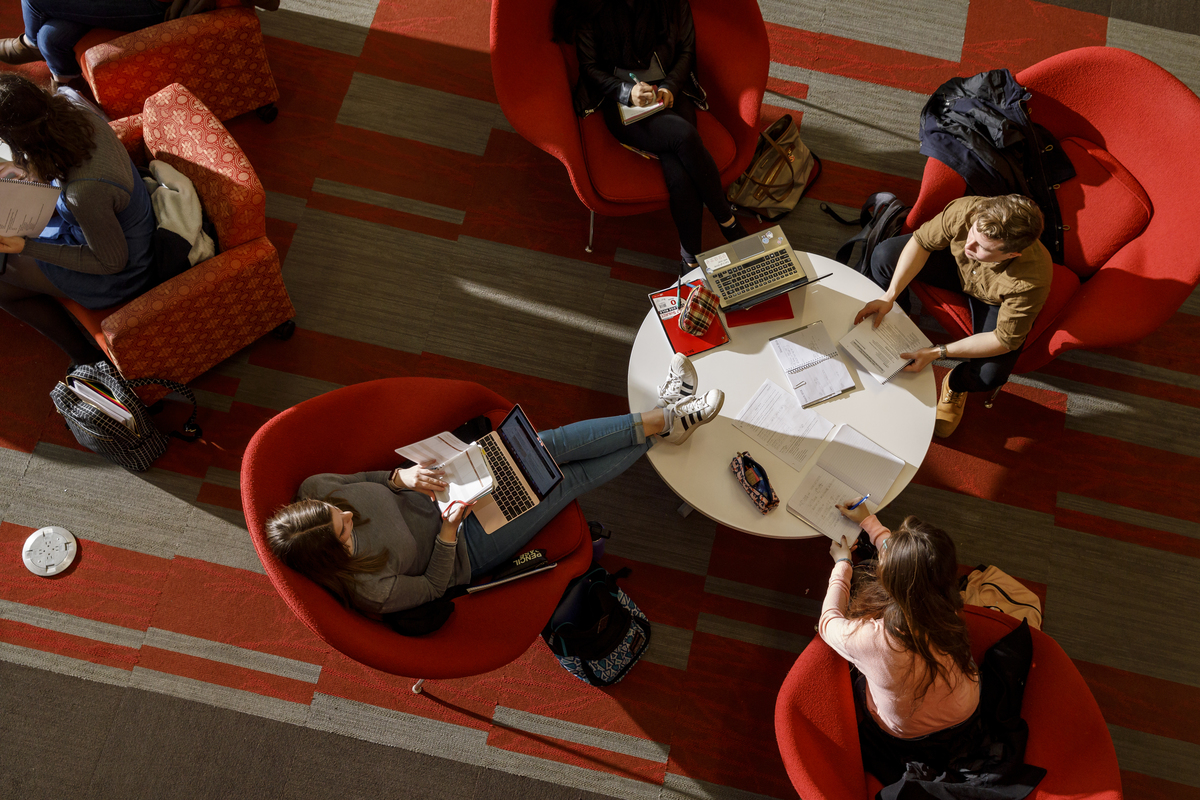 Aerial view of four students studying together in red chairs