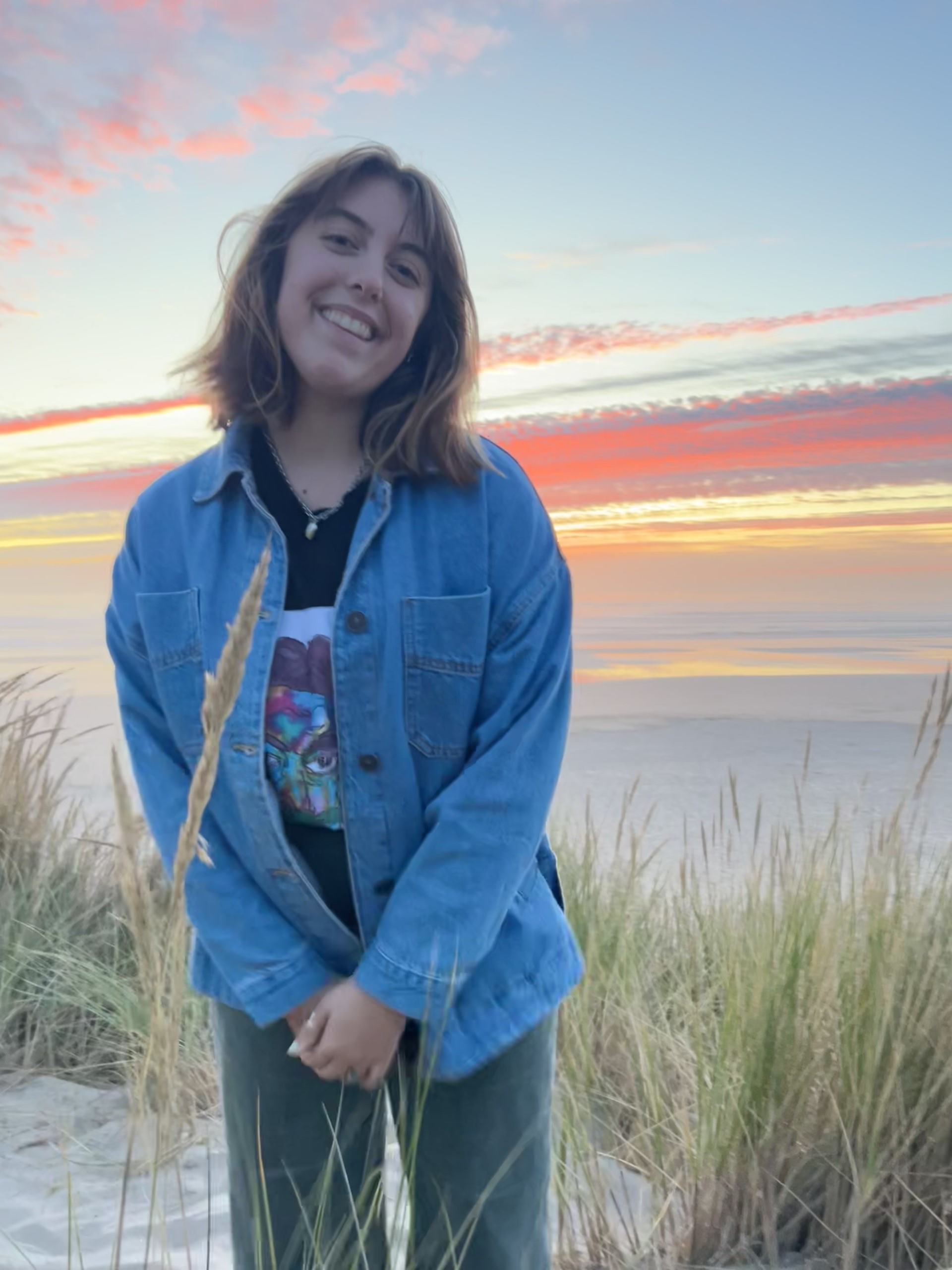 Kari standing in front of a sunset on the beach