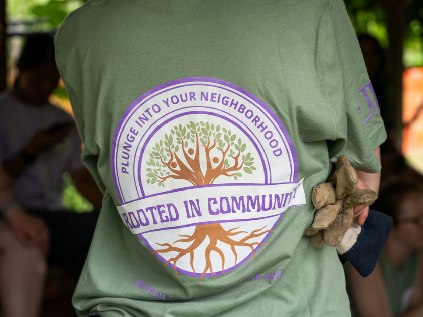 The back of a student shirt with the plunge into your neighborhood logo