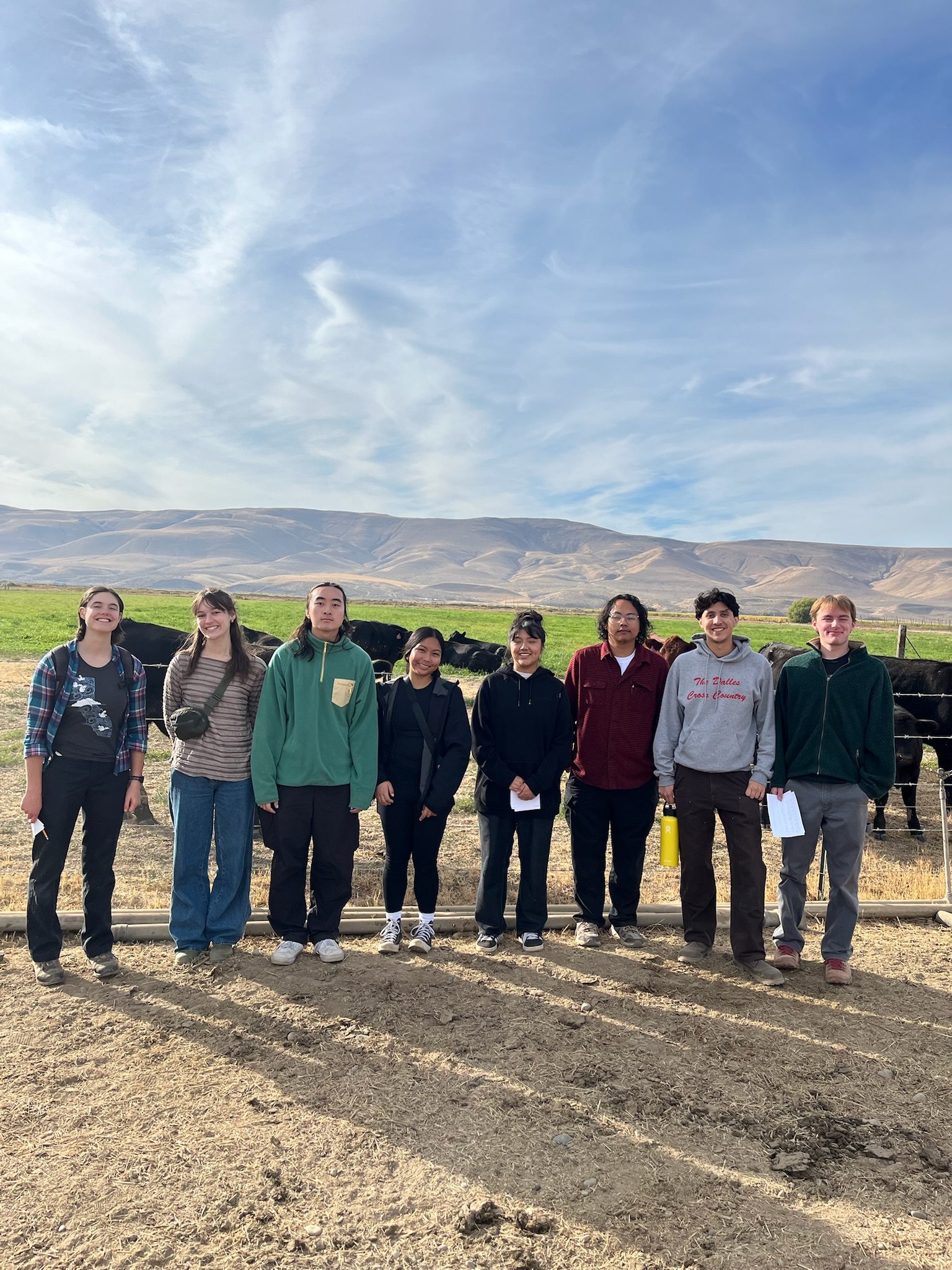 a group of 8 students on the rural immersion standing in front of hills