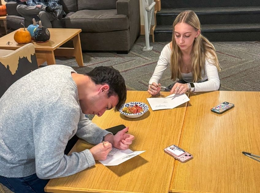 Students signing cards at a table