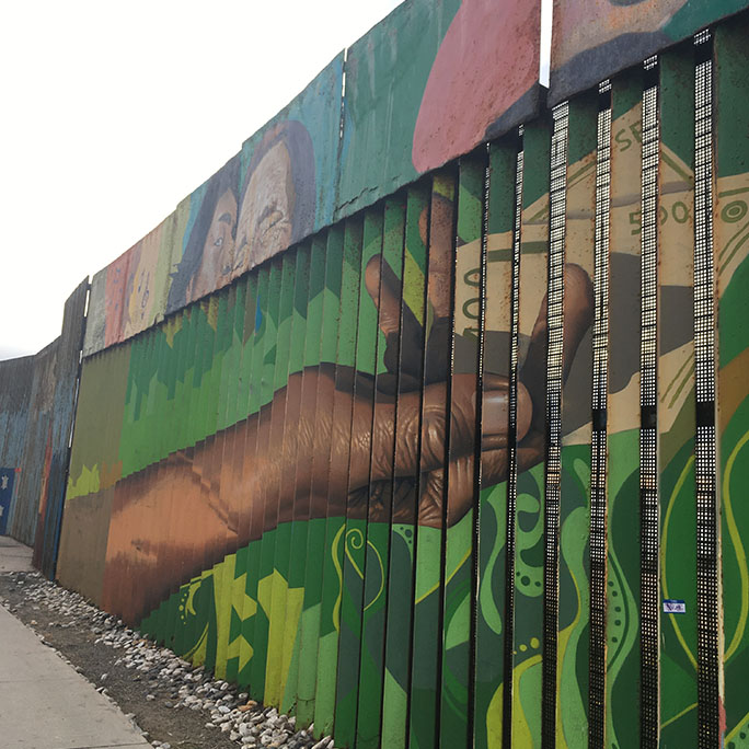 Border wall with artwork on it of a hand holding money.