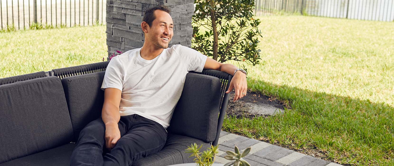 Luis Robles sitting on a sofa outside.