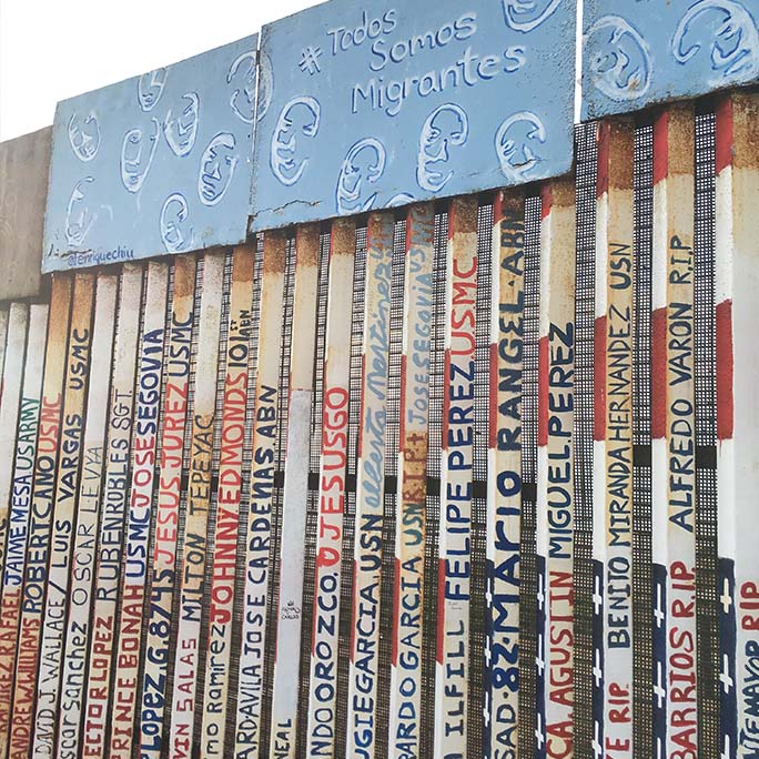 Border wall with names written upon the slats.