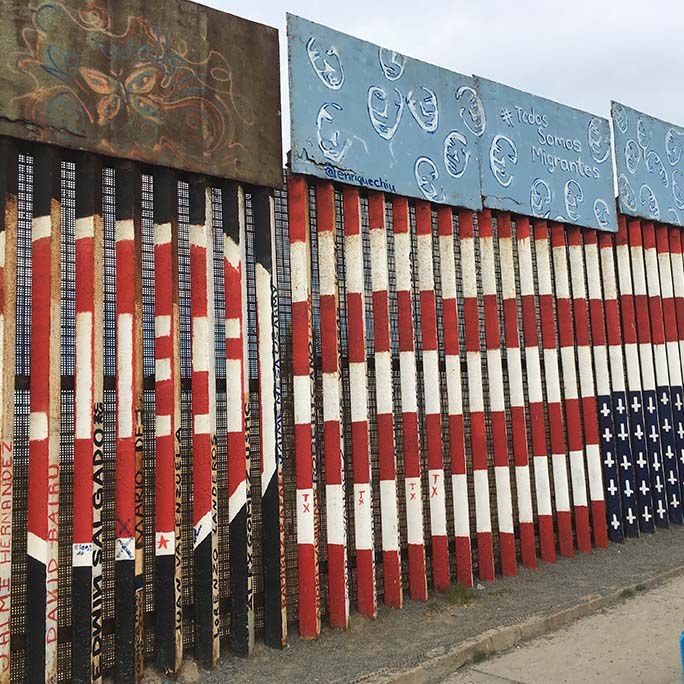 Border wall with an upside down flag and the word lies upon it. 