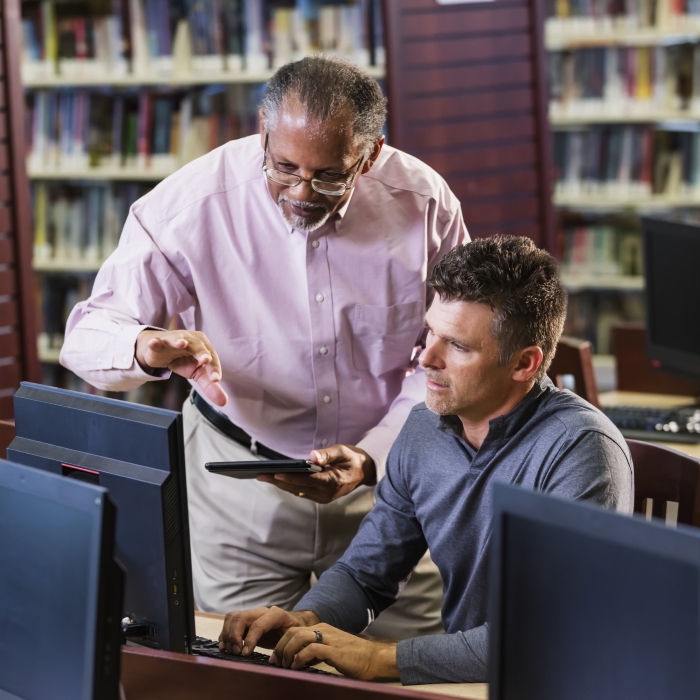 Two people working at a computer in a library