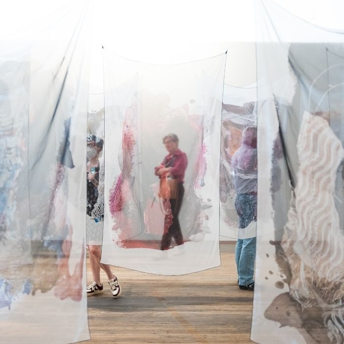 An art gallery installation with layers of gauzy fabric suspended from the ceiling