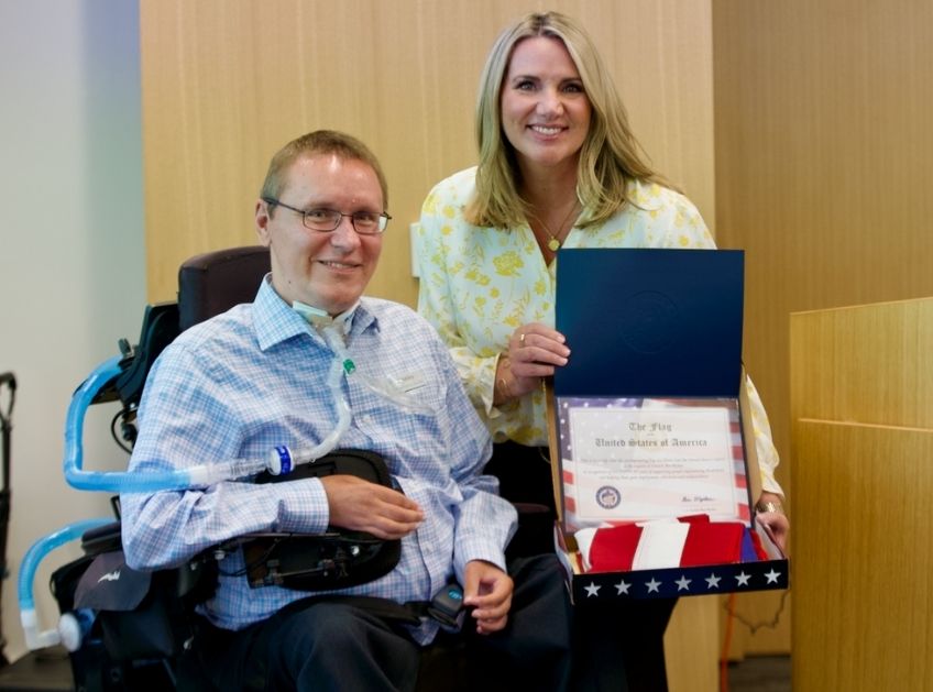 Scott Hatley at the INCIGHT anniversary celebration posing with a flag flow at the US capitol as well as a certificate of recognition for the organization