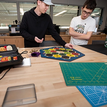 Two students manipulate a design in progress in the maker lab