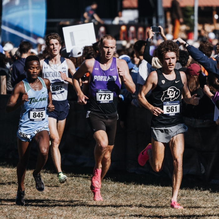 Matt Strangio runs in a pack with 3 others athletes at an outdoor cross-country race.