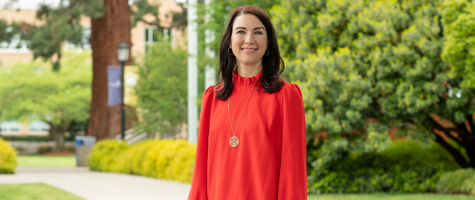 Gina poses in a red shirt near Clark Library on the UP campus.