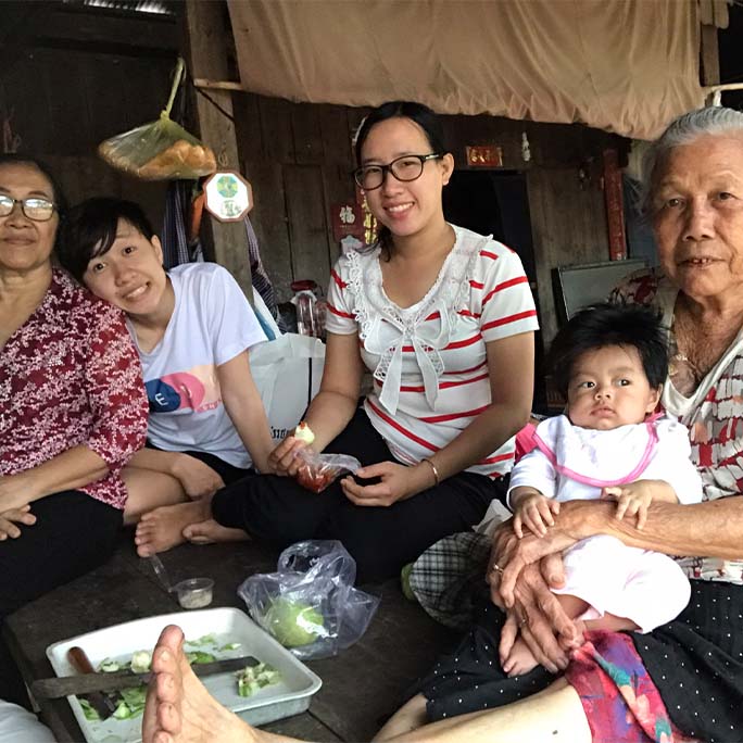 Four adults and a baby sit on a couch together.