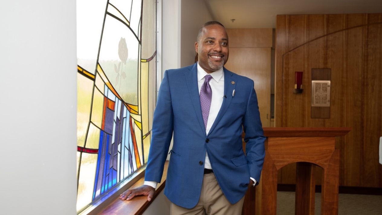 Dr. Kelly standing in front of an art glass window