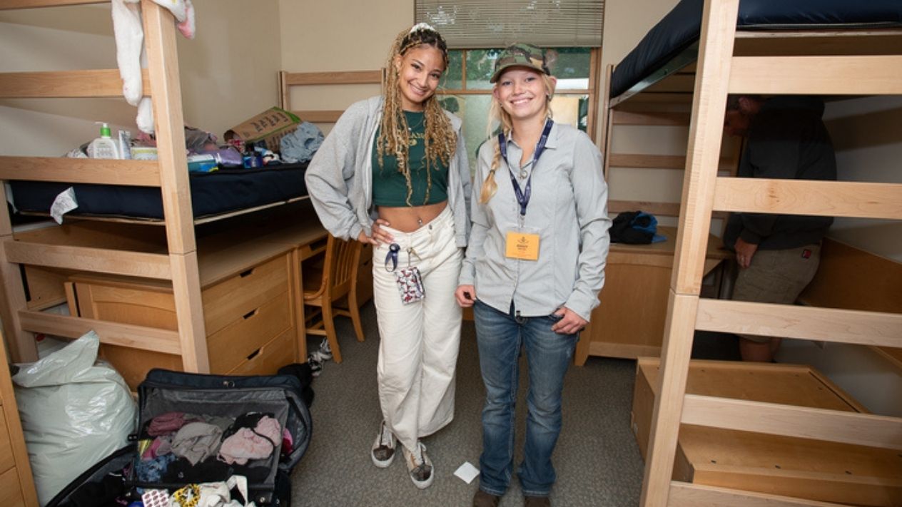 Two friends pose for a picture while moving into their dormitory room