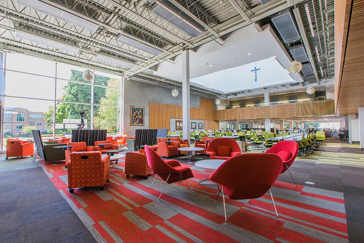 Interior view of first floor of library - airy open space with mid-century modern furnishings, bright oranges, lofted ceiling